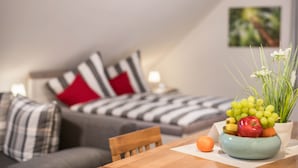 Una sala de estar moderna con un sofá, una mesa de comedor con fruta y una planta en maceta.
