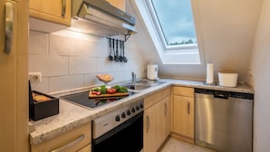 Una cocina con horno empotrado, lavavajillas y ventana sobre el fregadero.