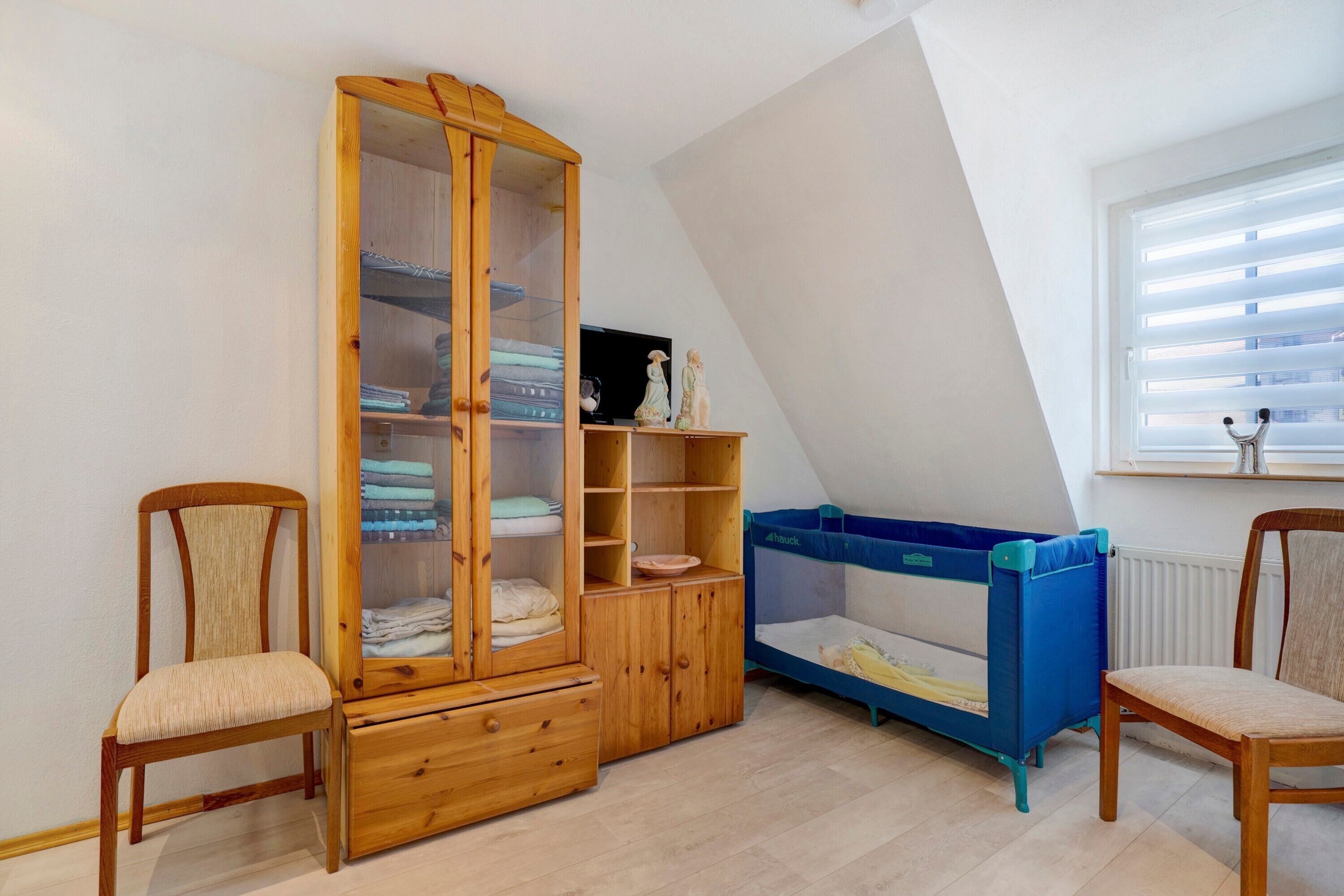 A room with a wooden cabinet, a bunk bed, and two chairs.
