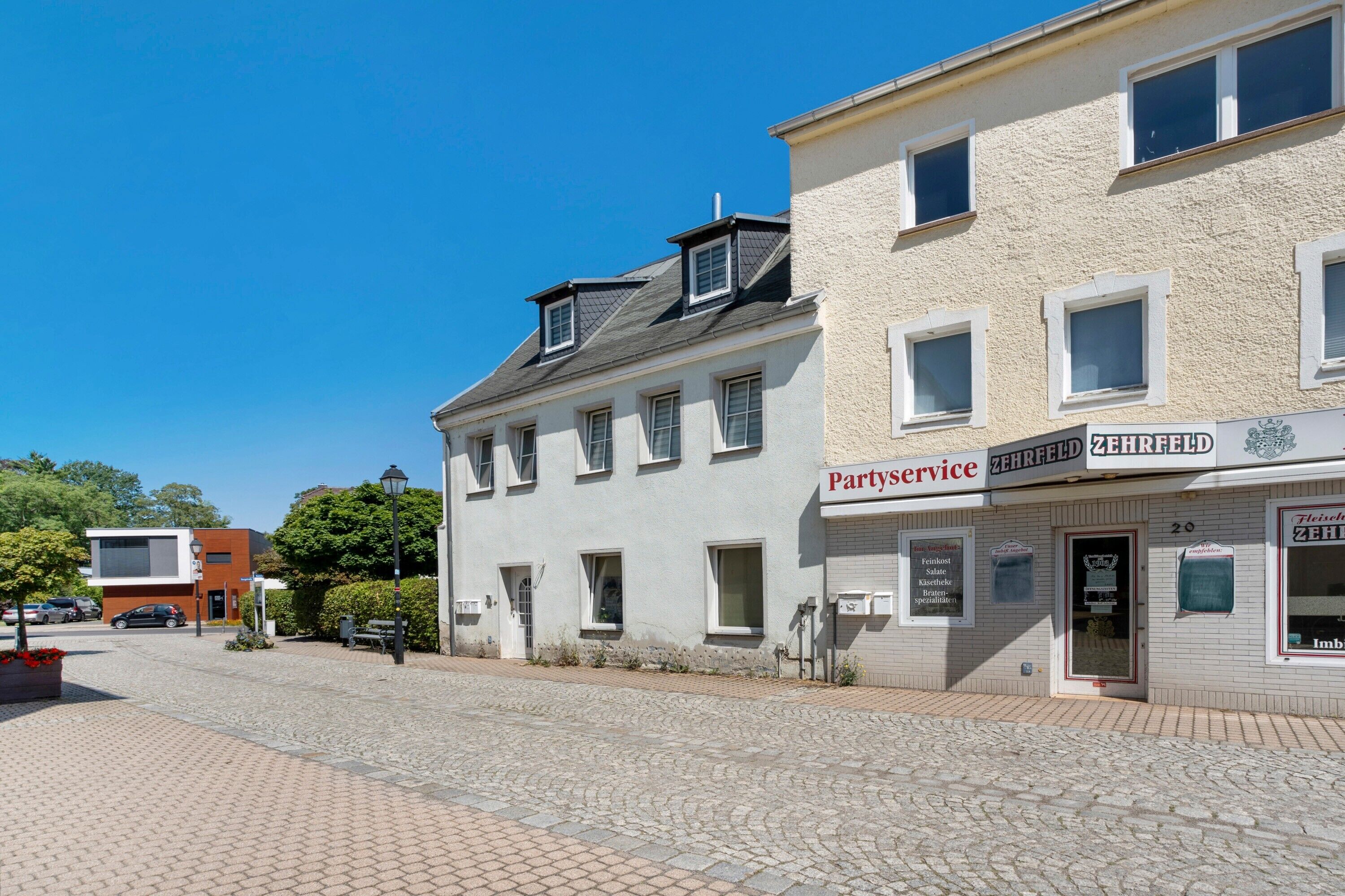 Une rue bordée d’immeubles, dont l’un affiche une enseigne indiquant « Service de traiteur pour fêtes ».