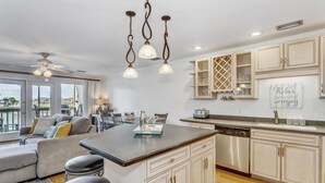 Une cuisine moderne dotée d’un îlot central, de meubles de couleur bois clair et d’un coin repas avec un canapé et des chaises.