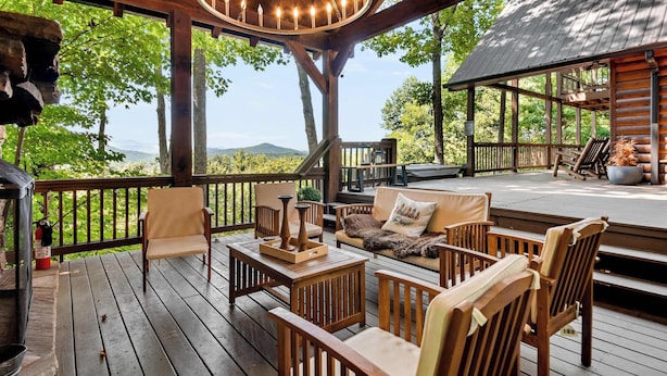 A wooden deck with outdoor furniture, a hanging light fixture, and a view of the mountains.