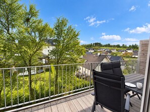 En balkong med utsikt över ett bostadsområde, en stol och ett bord.