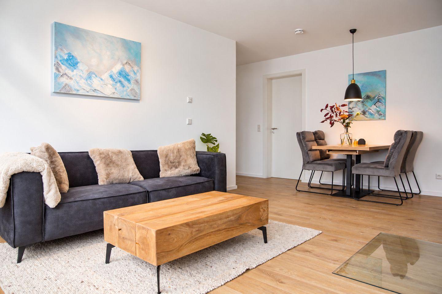 Un salon moderne comprenant un canapé, une table basse et un coin repas avec des chaises et une table.