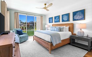 A hotel room with a bed, a desk, a chair, a nightstand, and a ceiling fan.