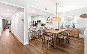A modern kitchen with white cabinetry, a wooden dining table, and wicker chairs.