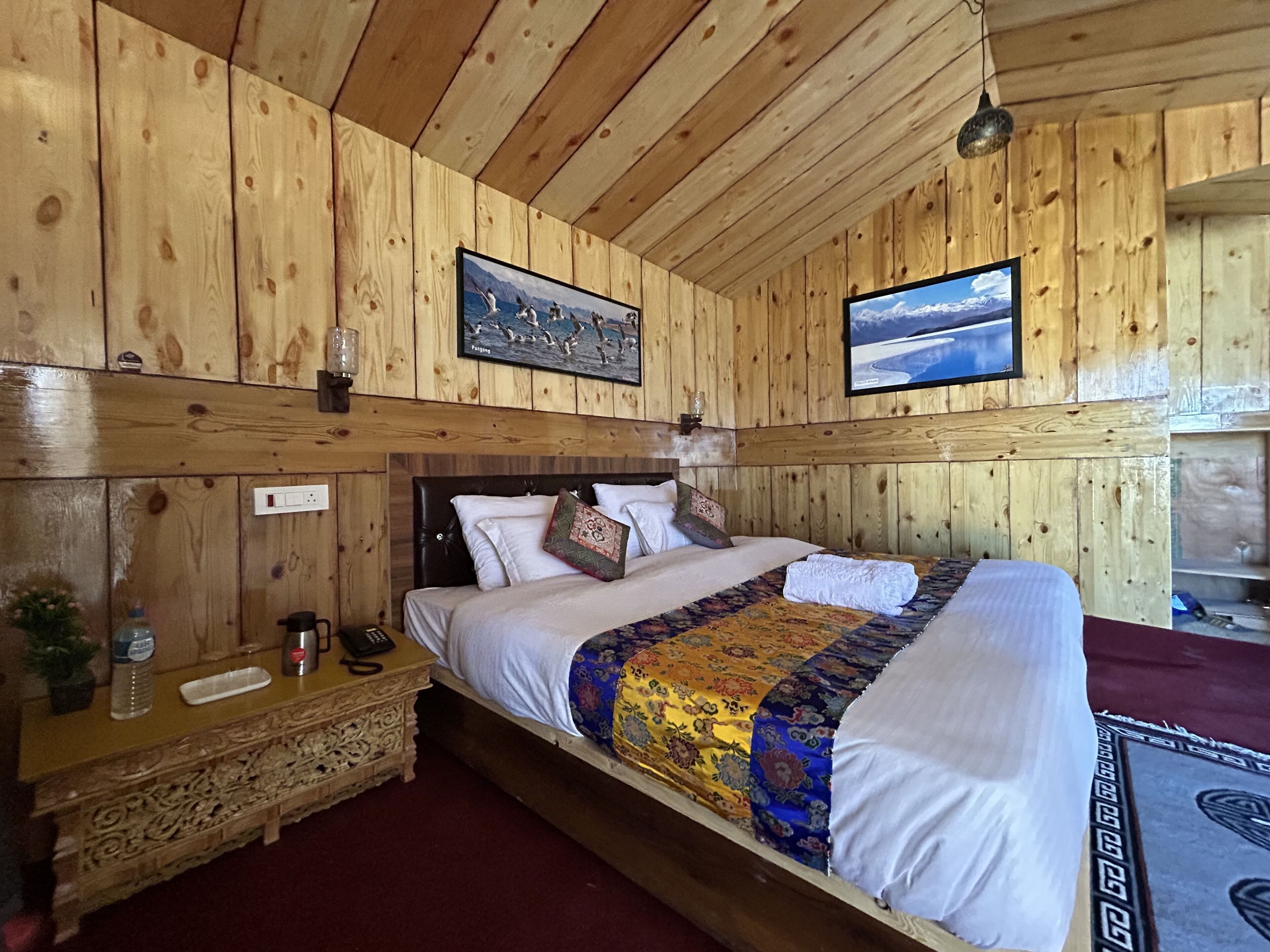 Una stanza con rivestimenti in legno, un letto, un comodino, una TV a parete e un quadro incorniciato.