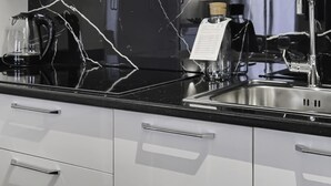 A kitchen with a black marble countertop, stainless steel sink, and white cabinets. - Italianway Comfort - Torino 57 A (Milan)