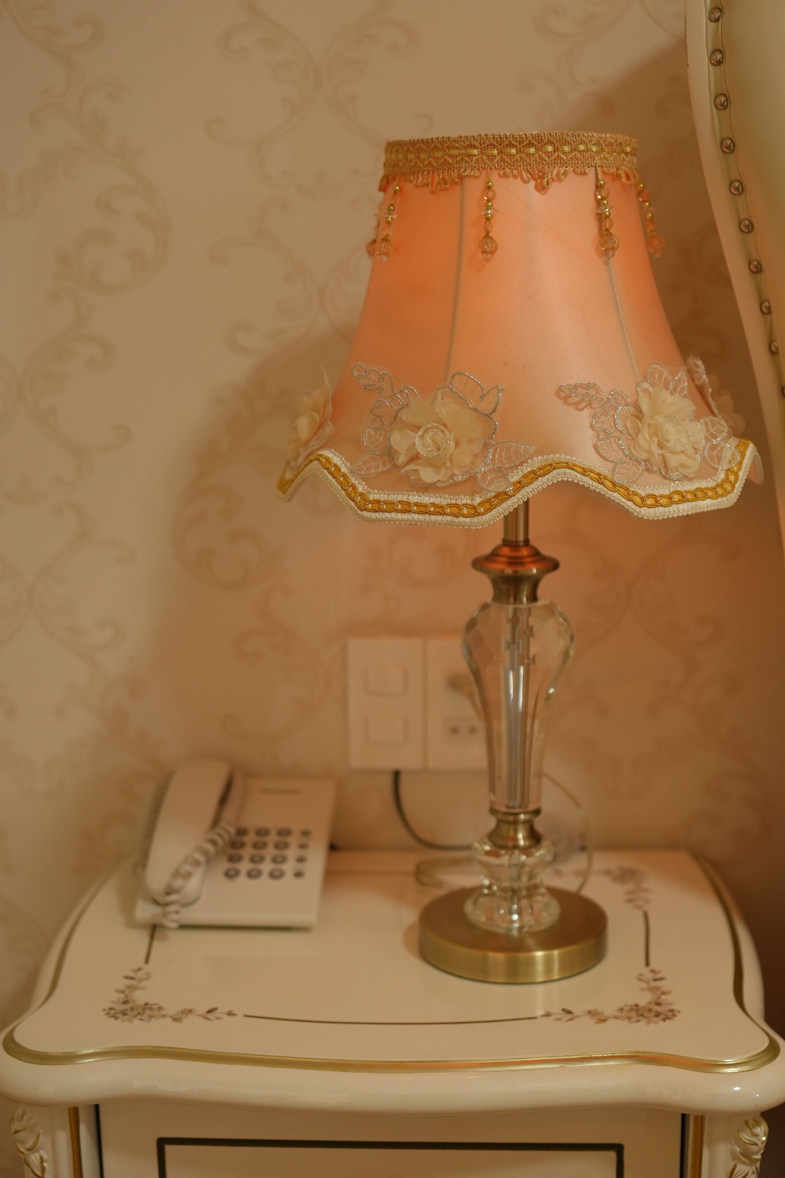 A vintage-style lamp with a floral design on a bedside table.