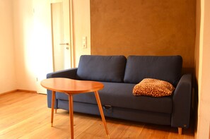 Une pièce avec un canapé bleu foncé, une table basse en bois et un coussin à motifs léopard.