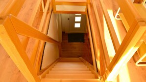 Una escalera de madera que conduce a una habitación con una puerta y una ventana.