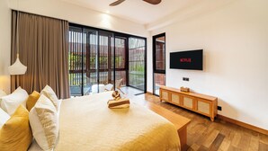 A modern hotel room with a large bed, a ceiling fan, a TV, and a balcony with a view. - Red Sunset Villa by Betterplace (Canggu)