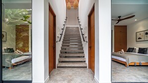 A staircase leading to a bedroom with a bed, a ceiling fan, and a view of a room with a bed and a plant. - Red Sunset Villa by Betterplace (Canggu)