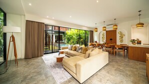 A modern living room with a sofa, coffee table, and dining area. - Red Sunset Villa by Betterplace (Canggu)