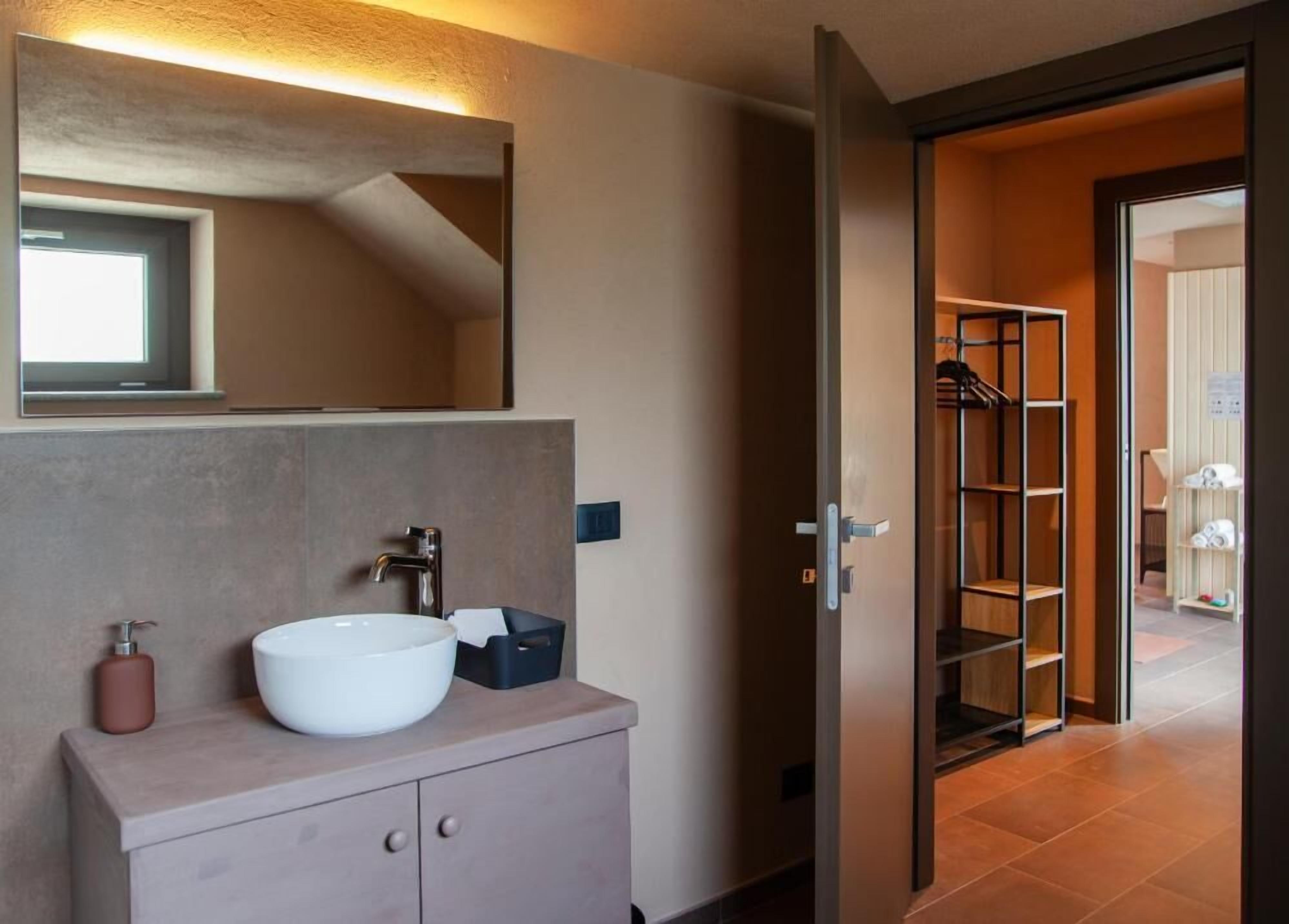A modern bathroom with a large mirror, a white sink, and a wooden vanity.