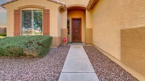 A building with a beige facade, a wooden door, and a window with shutters. - Perfect Retreat! 30 Nights Min! Raised Hot Tub With Views! (San Tan Valley)