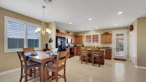 A spacious kitchen with a dining area, featuring a large island, wooden cabinets, and a modern chandelier. - Perfect Retreat! 30 Nights Min! Raised Hot Tub With Views! (San Tan Valley)