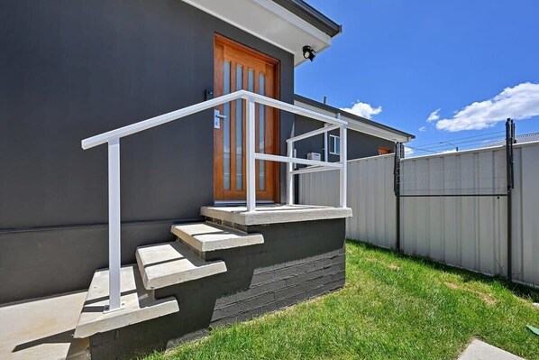 A modern house with a concrete staircase, a wooden door, and a metal fence.