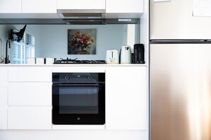 Moderni keittiö, jossa on sisäänrakennettu uuni, kahvinkeitin ja jääkaappi.