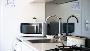 Une cuisine moderne équipée d’un four à micro-ondes, d’un évier et d’un robinet en acier inoxydable.