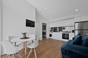 A modern kitchen with white cabinets, a built-in oven, and a stainless steel refrigerator.