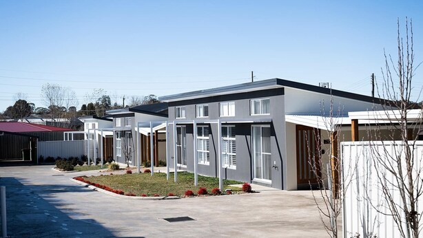 A modern residential area with multiple two-story houses featuring large windows and a flat roof design. - The Elm Apartments - The Cowhide Room (Orange)