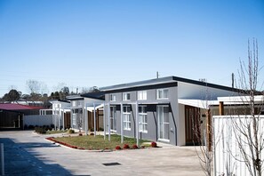 A modern residential area with multiple two-story houses featuring large windows and a flat roof design. - The Elm Apartments - The Cowhide Room (Orange)