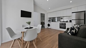 A modern kitchen with white cabinets, a built-in oven, and a stainless steel refrigerator.