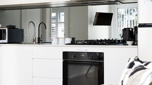 A modern kitchen with a built-in microwave, a gas stove, a dishwasher, and a large window providing natural light.