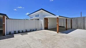 A modern two-story house with a covered patio area, a garage, and a fenced backyard.