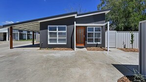 A modern two-story house with a covered patio, large windows, and a well-maintained driveway.