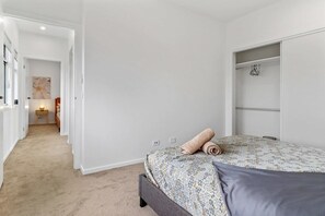 Ein Schlafzimmer mit einem Bett, einem begehbaren Kleiderschrank und einem Flur, der in einen anderen Raum führt.
