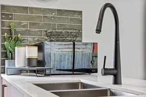 Eine Küche mit modernem Wasserhahn, einem Einbauofen und einer Spritzschutzwand mit Ziegelmuster.