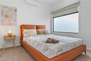 Un dormitorio con cama, mesita de noche, ventana y aire acondicionado instalado en la pared.