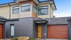 Ein modernes, zweistöckiges Haus mit flachem Dach, großen Fenstern und einer Garage.