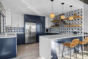 A modern kitchen with a central island, stainless steel appliances, and a patterned backsplash. - Waterfront | Pool | Hot tub | Boat Dock (Leander)