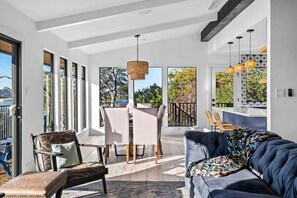 A modern living room with a sofa, chairs, a dining table, and large windows. - Waterfront | Pool | Hot tub | Boat Dock (Leander)