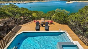 A pool with a view of a beach and ocean, surrounded by trees and a deck with lounge chairs. - Waterfront / Pool / Hot tub / Boat Dock (Leander)