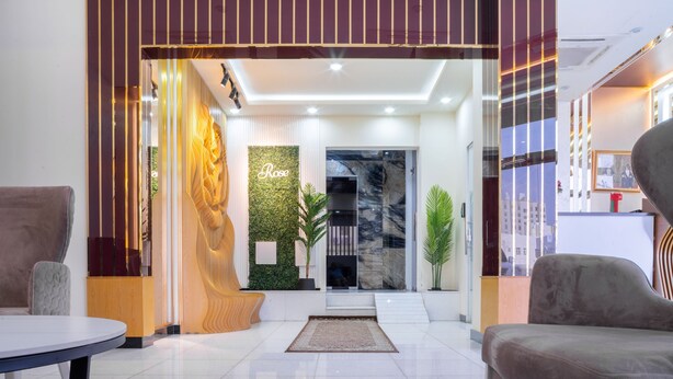 A modern lobby with a reception desk, a large plant, and a marble wall. - OYO Townhouse 156 Rose Hotel Apartments. (Seeb)