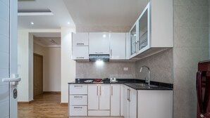 A modern kitchen with white cabinets, a black countertop, and a stainless steel sink. - OYO Townhouse 156 Rose Hotel Apartments. (Seeb)