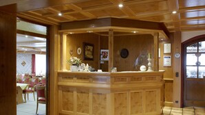 A reception area with a wooden counter, framed pictures, and a clock on the wall.