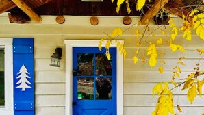 Une porte bleue avec un panneau de verre, un mur blanc et un symbole représentant un arbre sur le cadre de la porte.