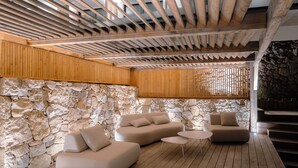 Un intérieur moderne avec un mur en pierre, un plafond en bois et un ensemble de canapés.