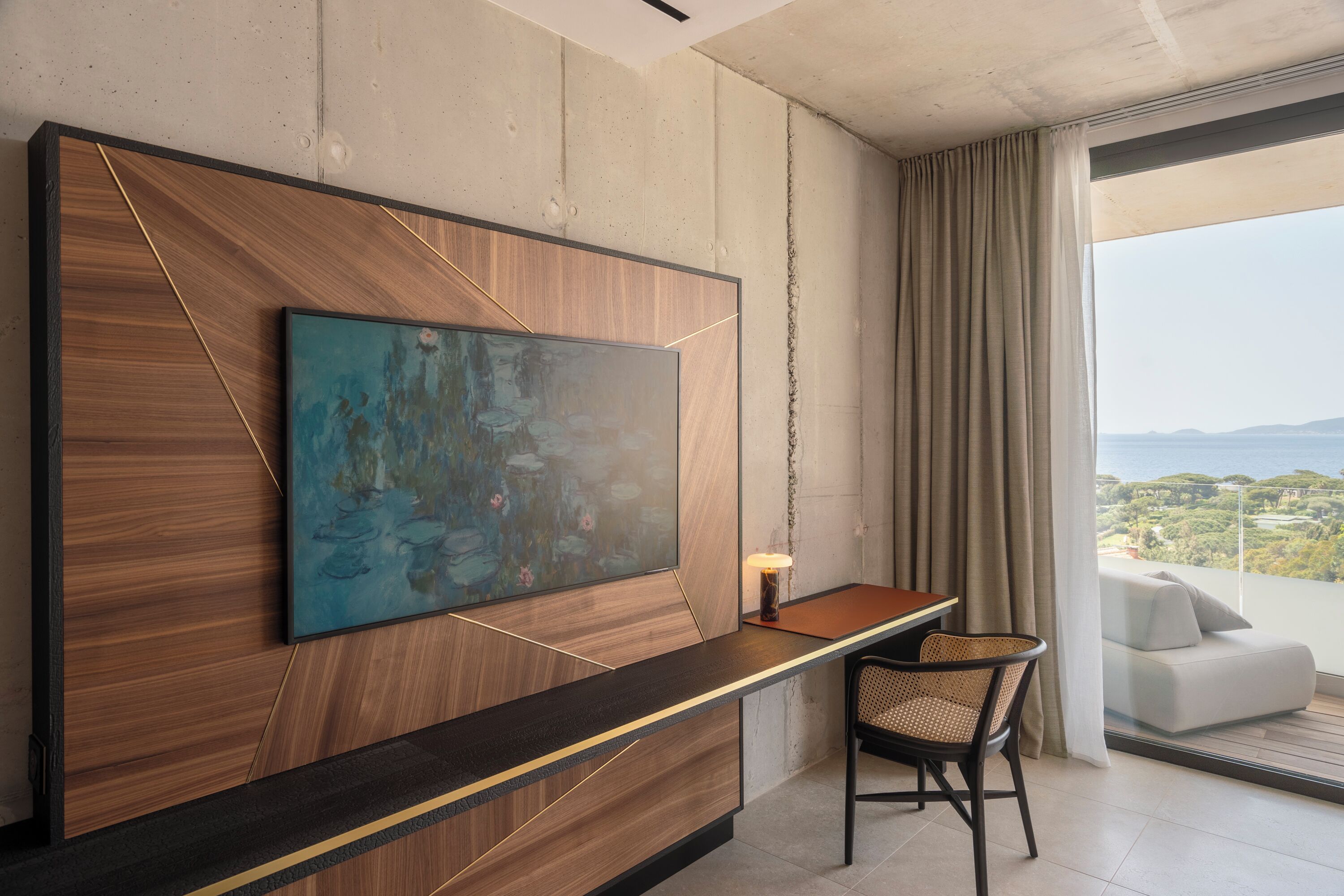 A modern hotel room with a large abstract painting on the wall, a wooden accent wall, a desk with a chair, and a view of the outdoors.