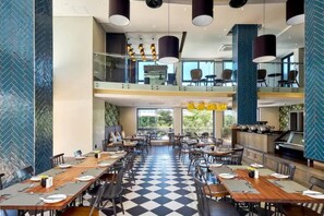 A spacious dining area with multiple tables and chairs, a checkered floor, and a kitchen area visible in the background. - Luxury Self Catering 1 Bed Apart (Pretoria)
