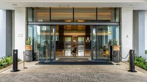 Ein moderner Hotel Eingang mit Glastür, einer Rezeption und einer schwarzen Fußmatte.