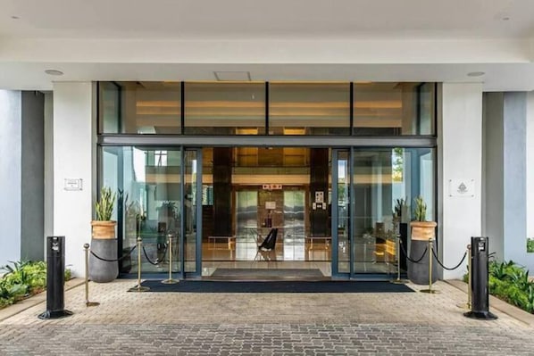 A modern hotel entrance with a glass door, a reception desk, and a black mat at the entrance. - Luxury Self Catering 1 Bed Apart (Pretoria)