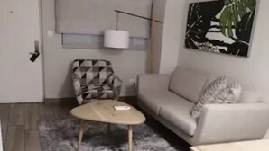 A living room with a sofa, a patterned armchair, a coffee table, a lamp, and a painting on the wall. - Luxury Self Catering 1 Bed Apart (Pretoria)