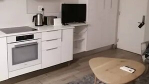 A modern kitchen with white cabinets, a built-in oven, a coffee maker, and a flat-screen TV. - Luxury Self Catering 1 Bed Apart (Pretoria)