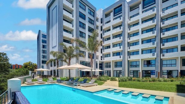 A modern hotel with a swimming pool, multiple balconies, and outdoor seating areas. - Premier Lifestyle at The Regency (Pretoria)